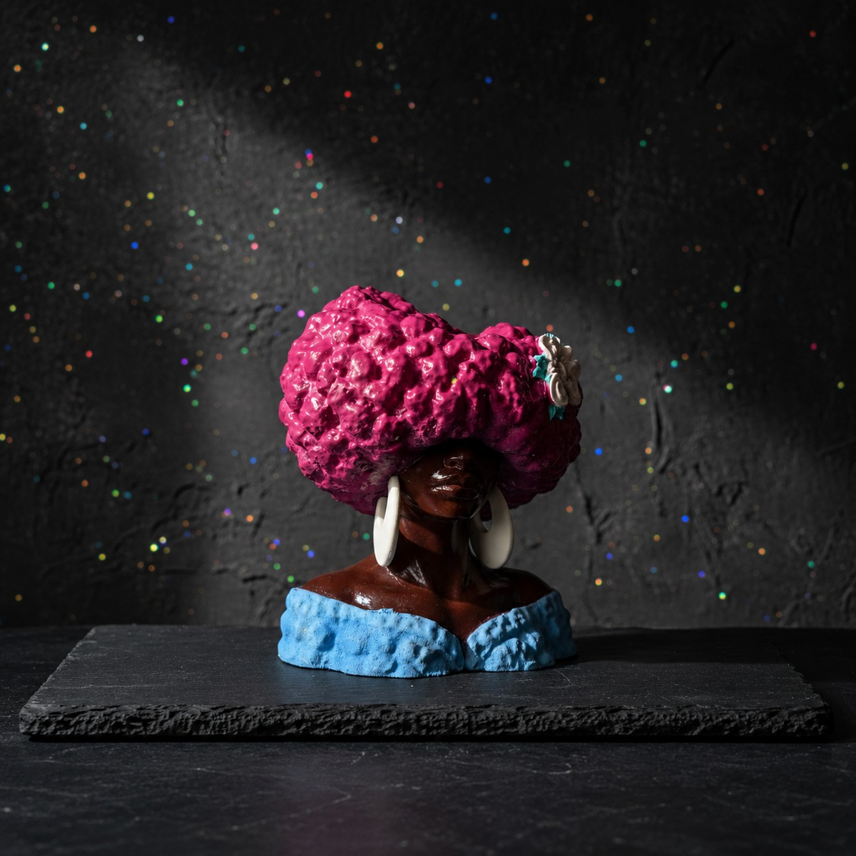 Unplanted Girl Juice head planter on a dark surface with pink textured hair and blue base