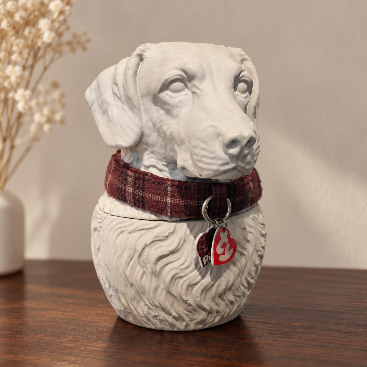 White dog portrait urn wearing a tartan collar and hanging tags without the bow.