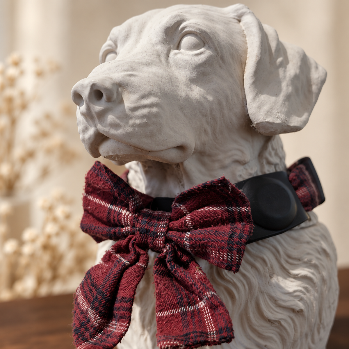 Close detail of the chalk white sculpted dog face and tartan collar with bow.