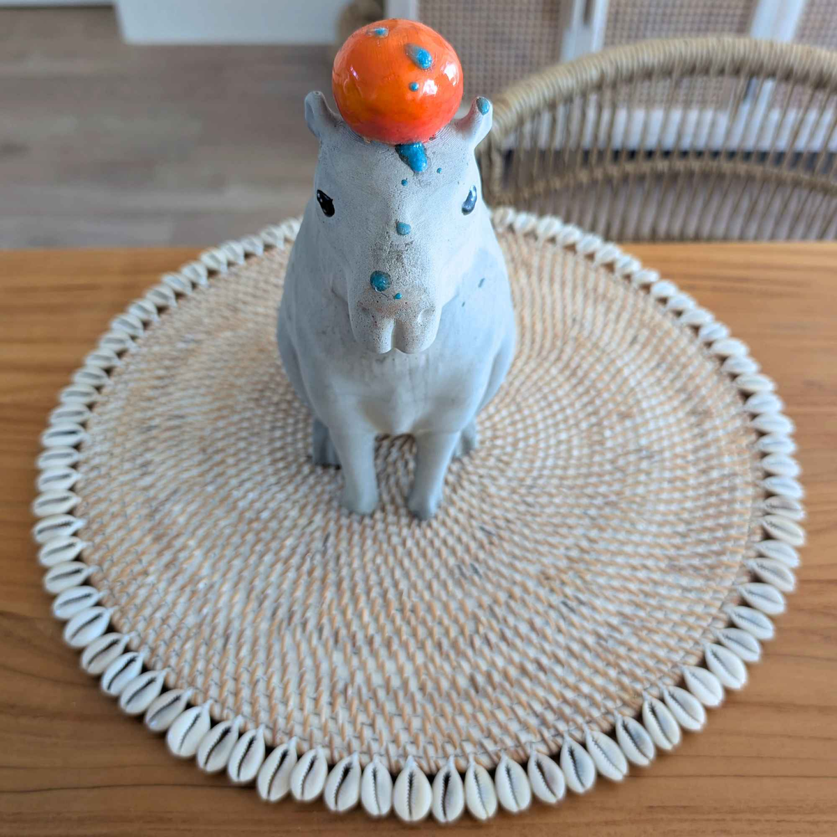 Top-down view of capybara ornament on a round woven mat