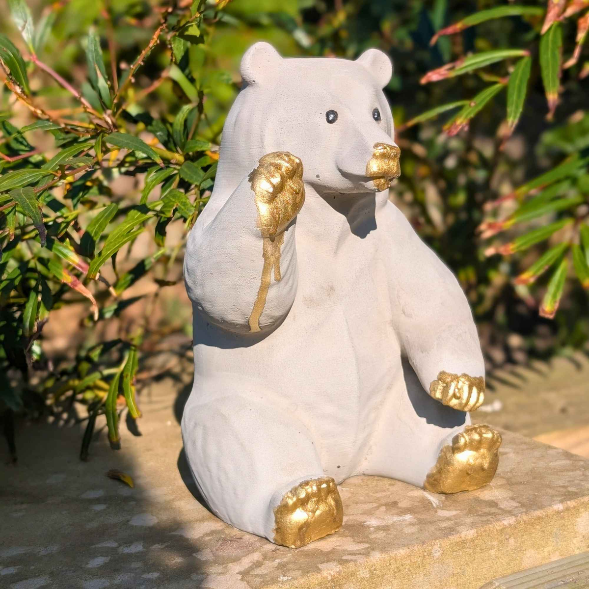 Honey bear garden ornament angled on a wooden garden bench