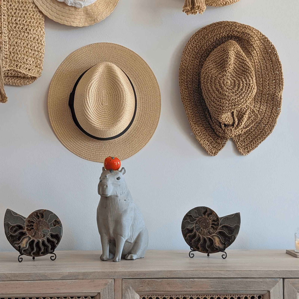 Small capybara ornament on a shelf between two carved decorations