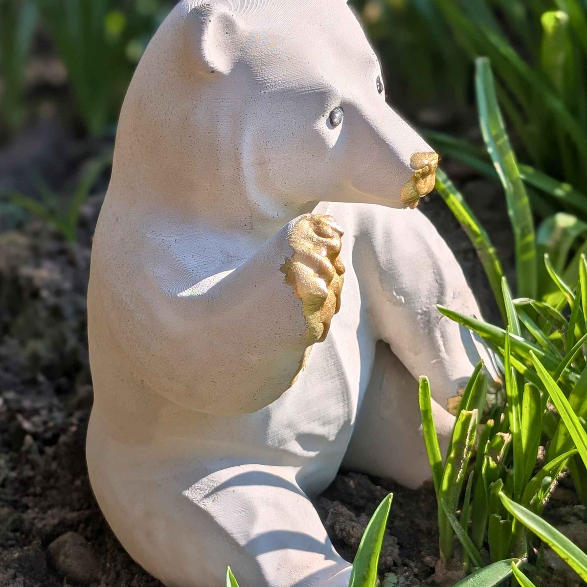 Side view of honey bear garden ornament among green plants outdoors