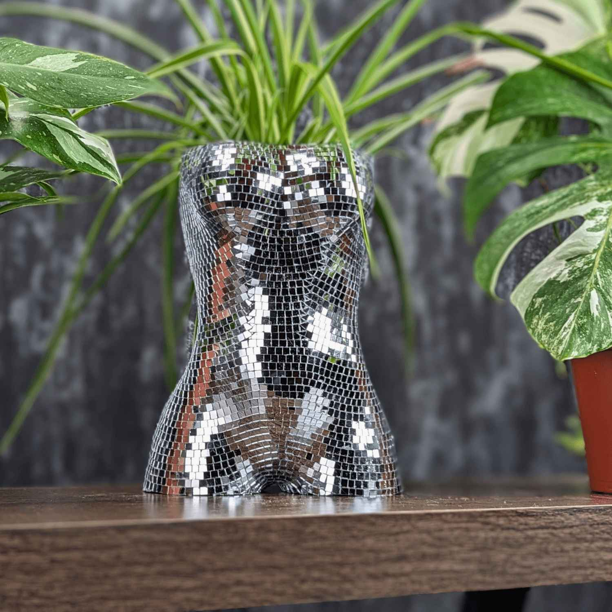 Silver mirror mosaic torso planter with a green houseplant, front view