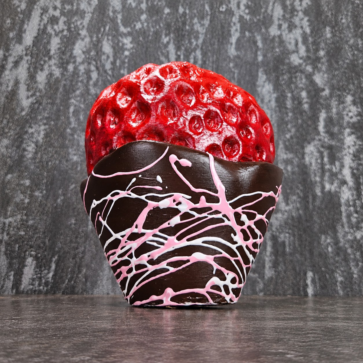 Chocolate-dipped strawberry planter with pink drizzle, planted with a spider plant