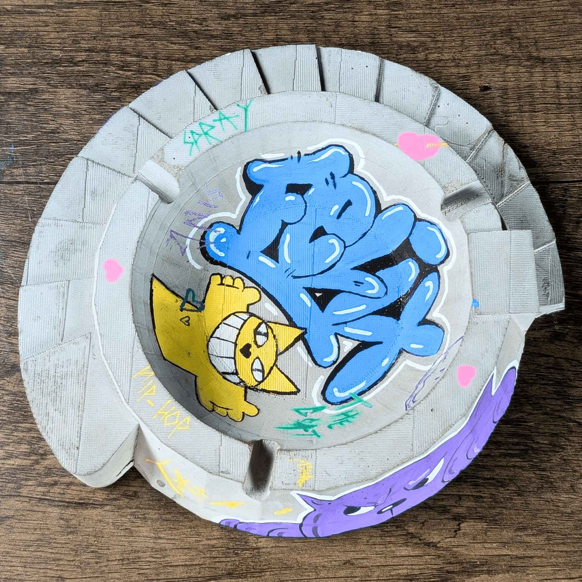 Top-down view of custom ashtray showing blue and yellow graffiti art