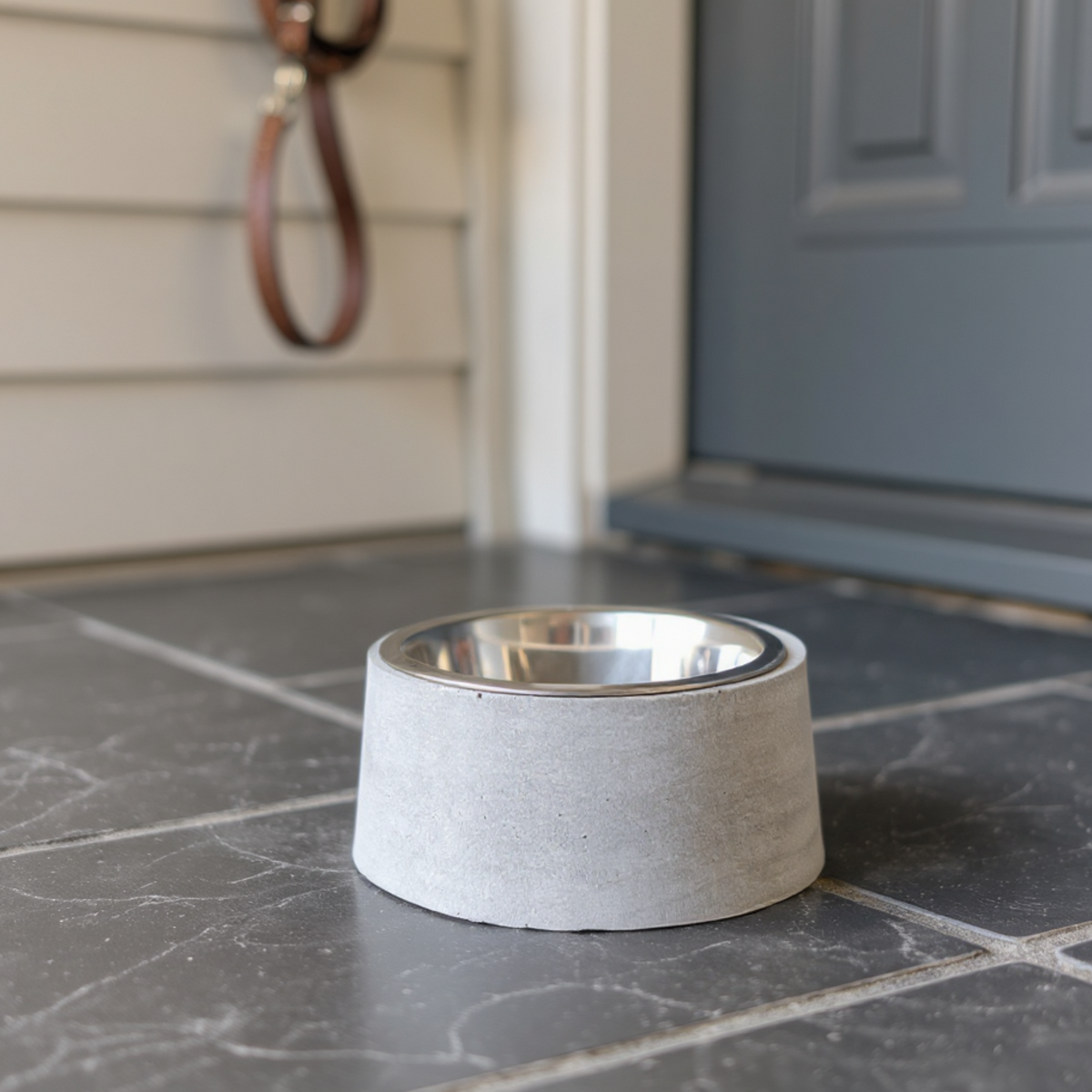 Cast stone dog bowl with steel insert beside an entrance door