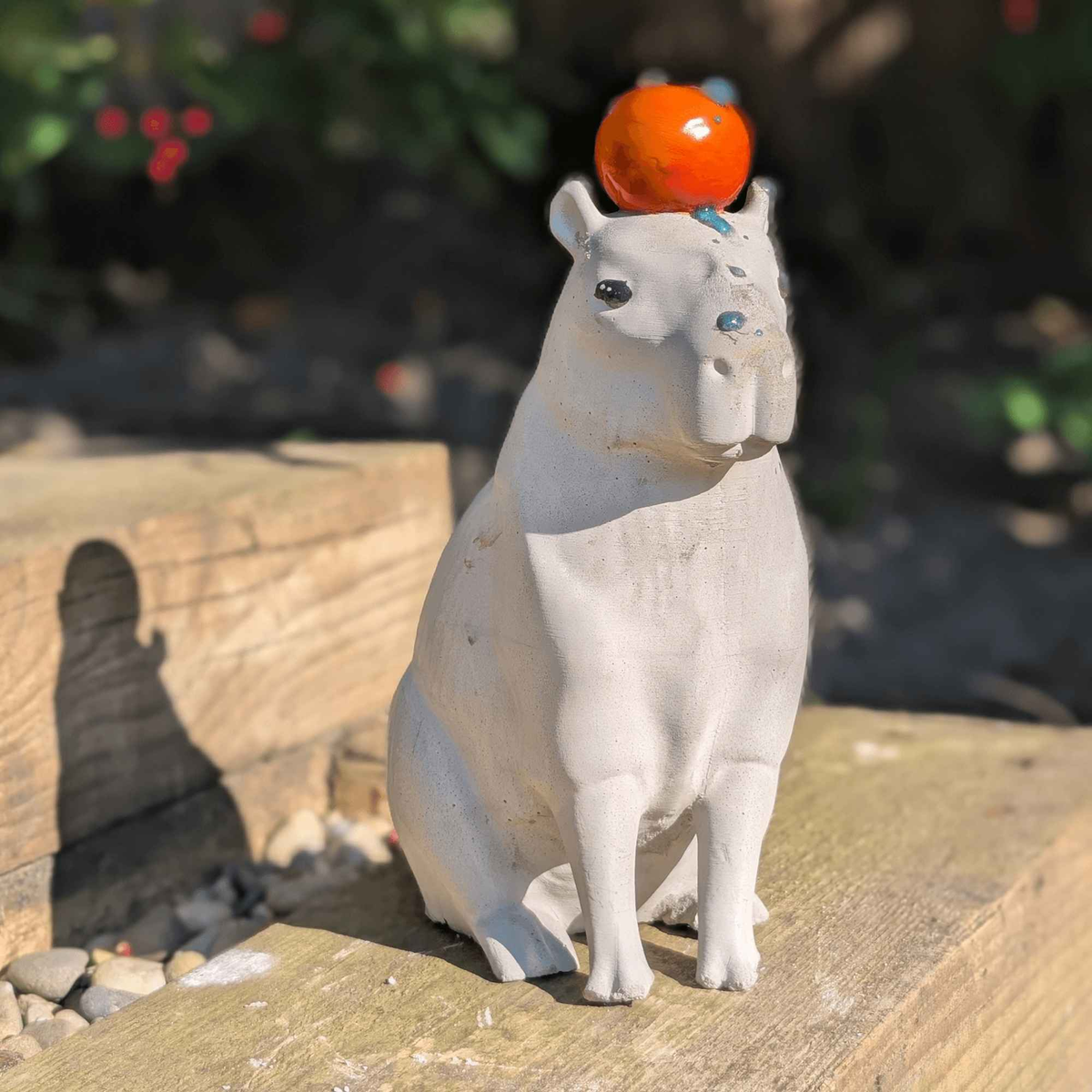 Front view of capybara garden ornament on a wooden sleeper