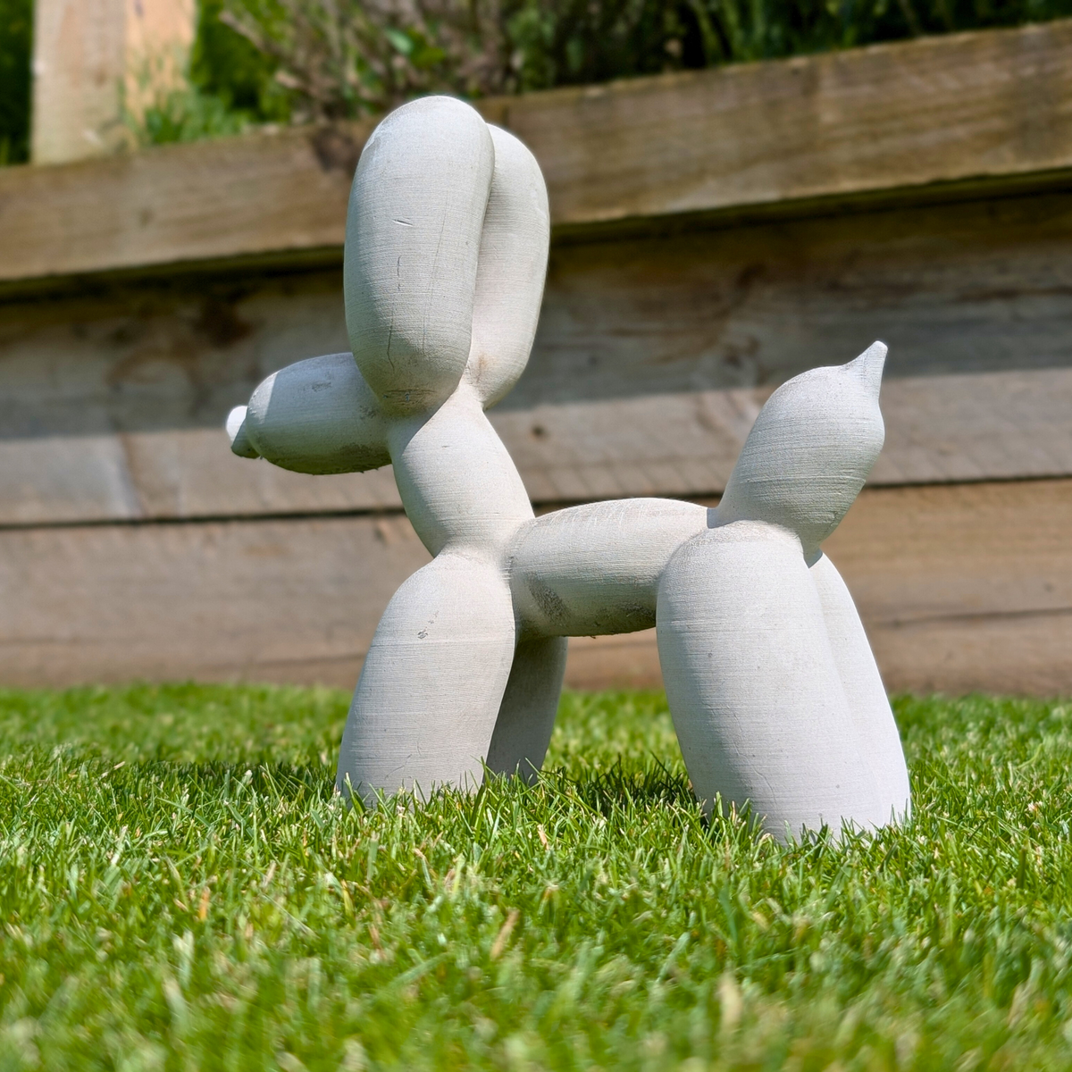 Cast stone balloon dog ornament standing on grass