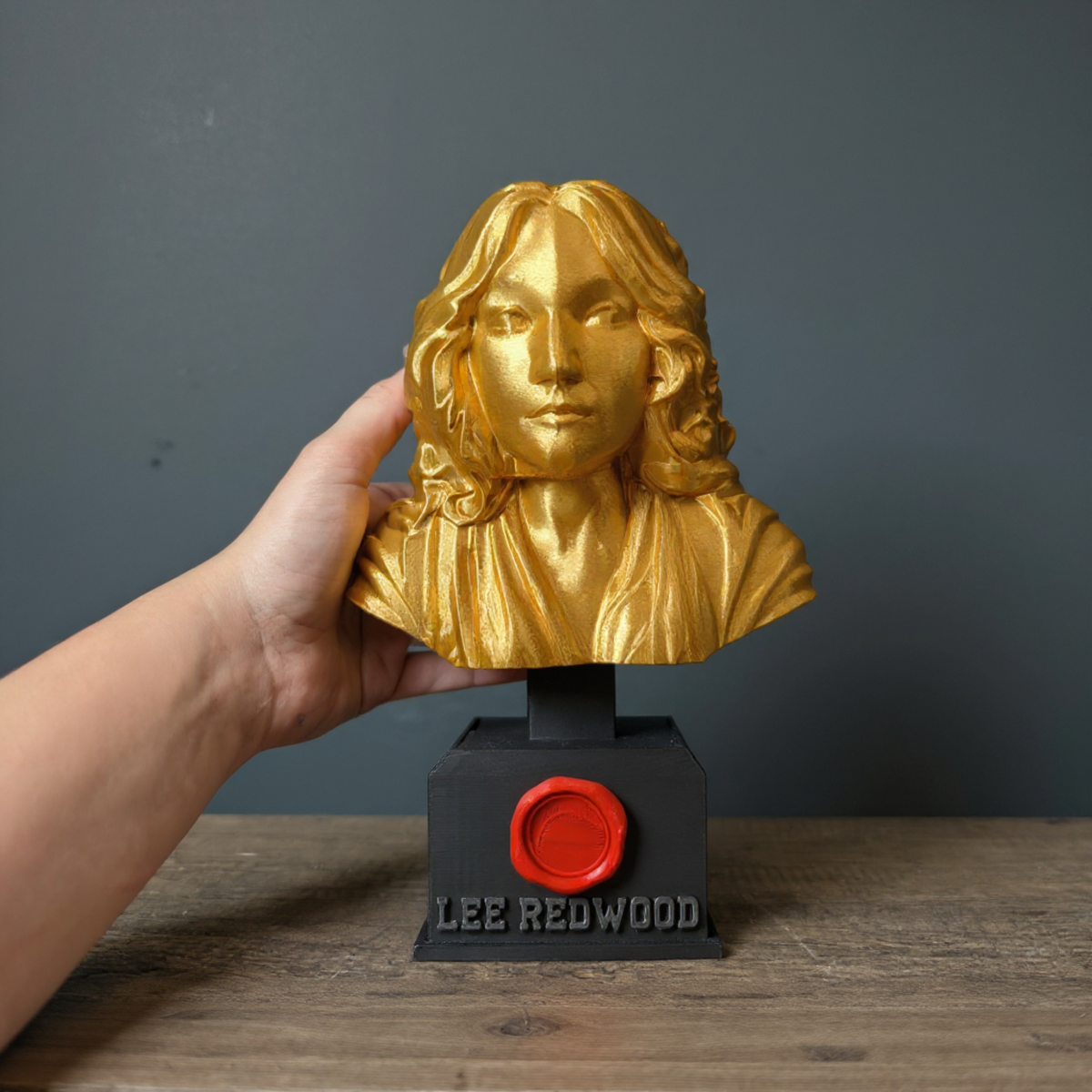 Personalised gold bust trophy held in one hand for scale