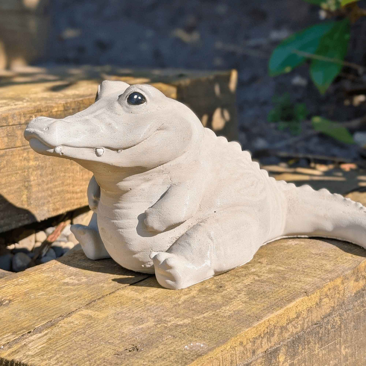 Side view of the cast stone crocodile ornament on a wooden garden step