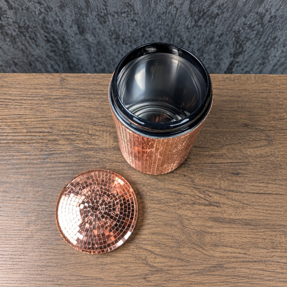 Top view of an open rose gold mirror canister with detached lid