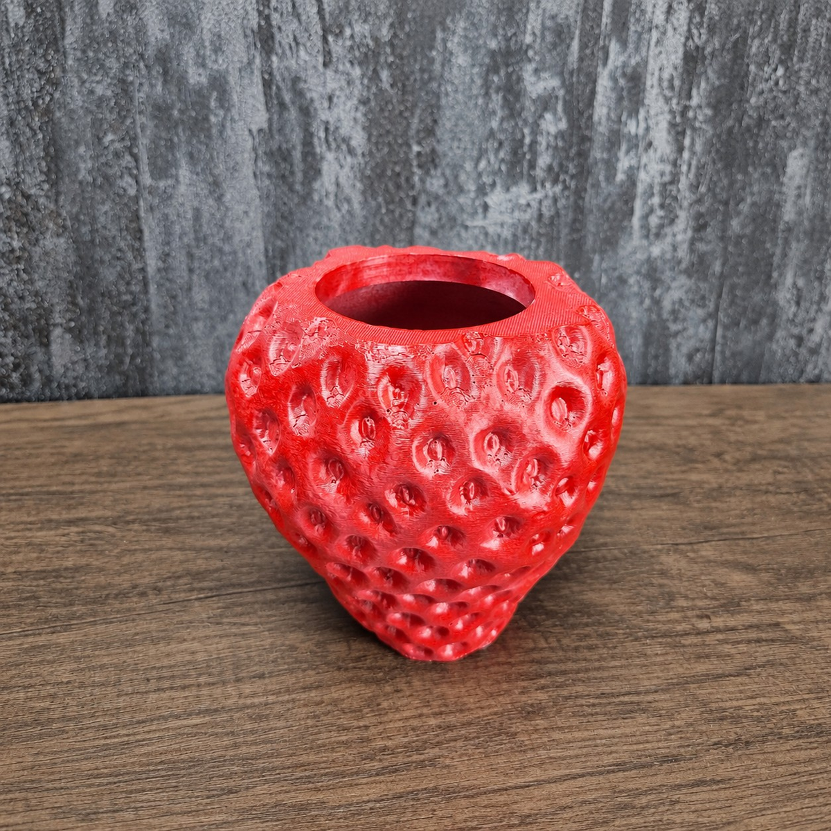 Unplanted red strawberry-shaped planter shown front-on