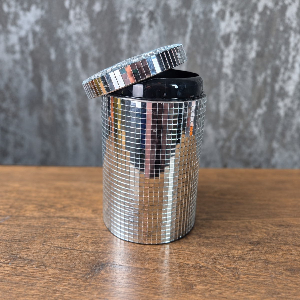 Open silver mirror canister with its hinged lid raised