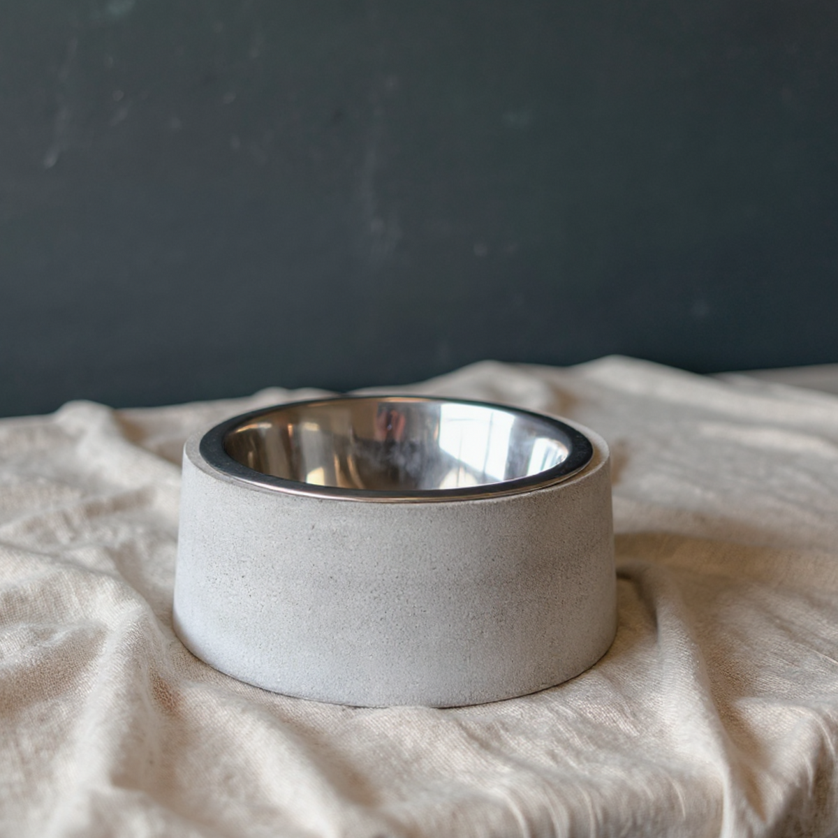 Cast stone pet bowl with steel insert displayed on soft fabric