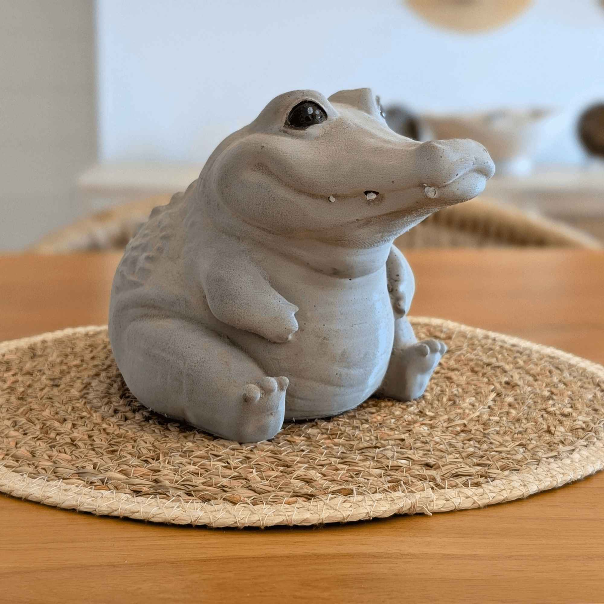 Cast stone crocodile ornament styled indoors on a woven table mat