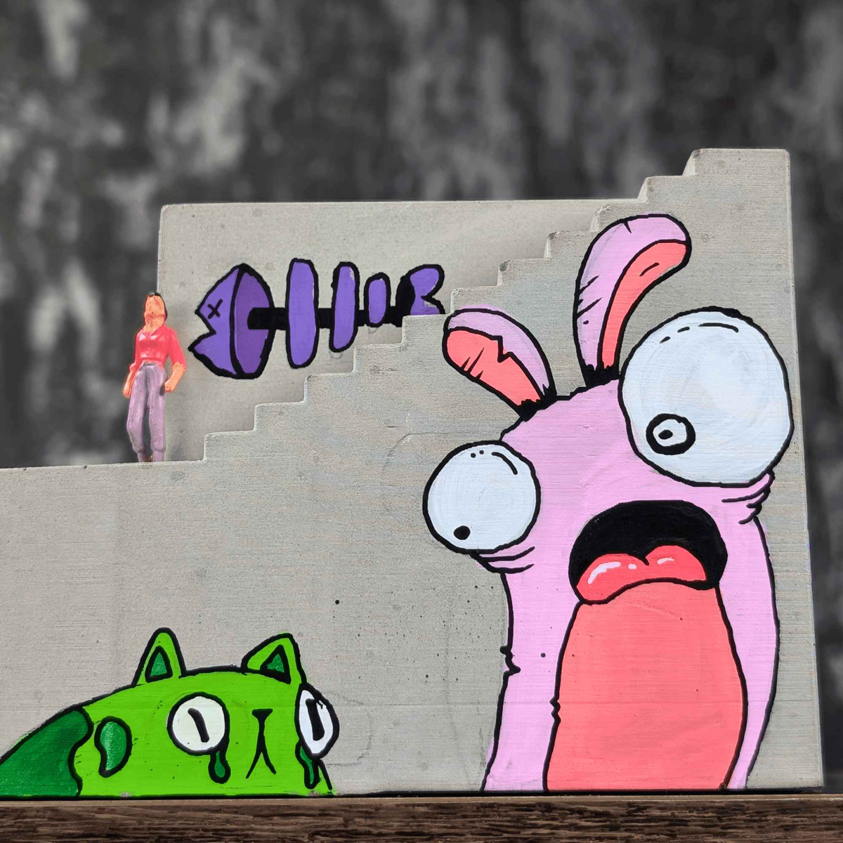 Close-up of pink rabbit and green creature murals on the planter side