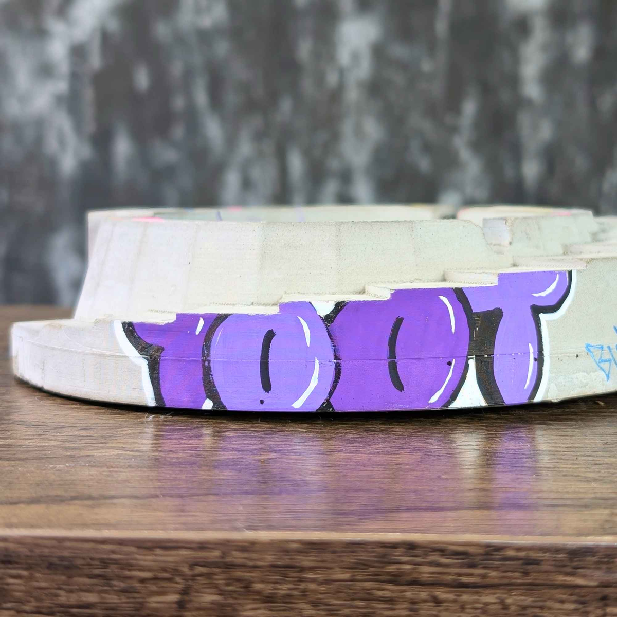 Custom concrete ashtray side detail with purple graffiti lettering
