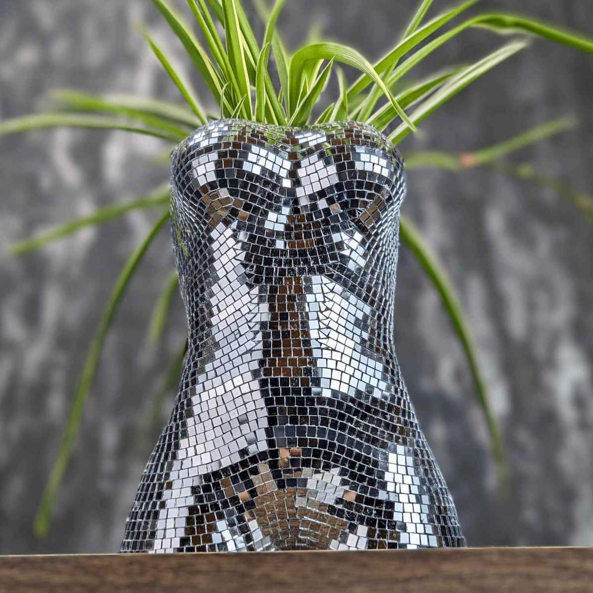 Close-up of planted mirror torso planter and green leaves