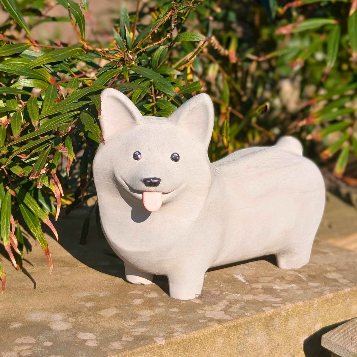 Corgi Garden Ornament: pale corgi among leafy garden plants