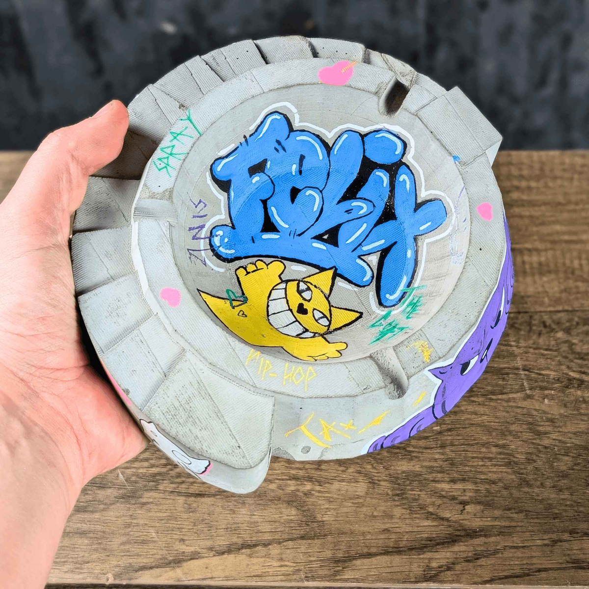 Custom graffiti ashtray held in one hand, showing blue and yellow artwork