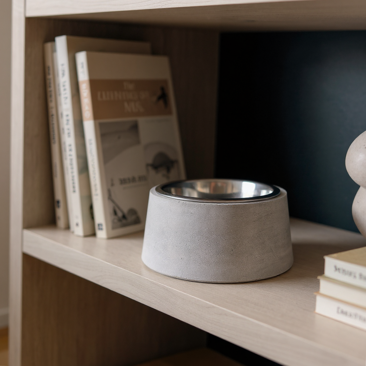 Cast stone pet bowl with steel insert displayed on a wooden shelf