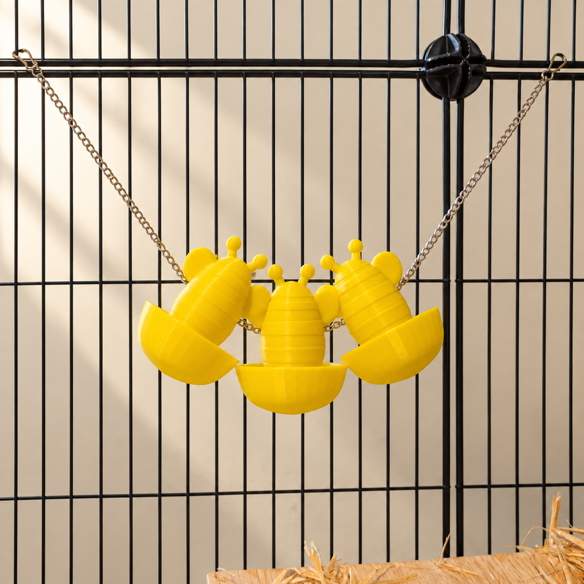 Three yellow bee forage cups on one chain, with clips securing both ends to cage bars.
