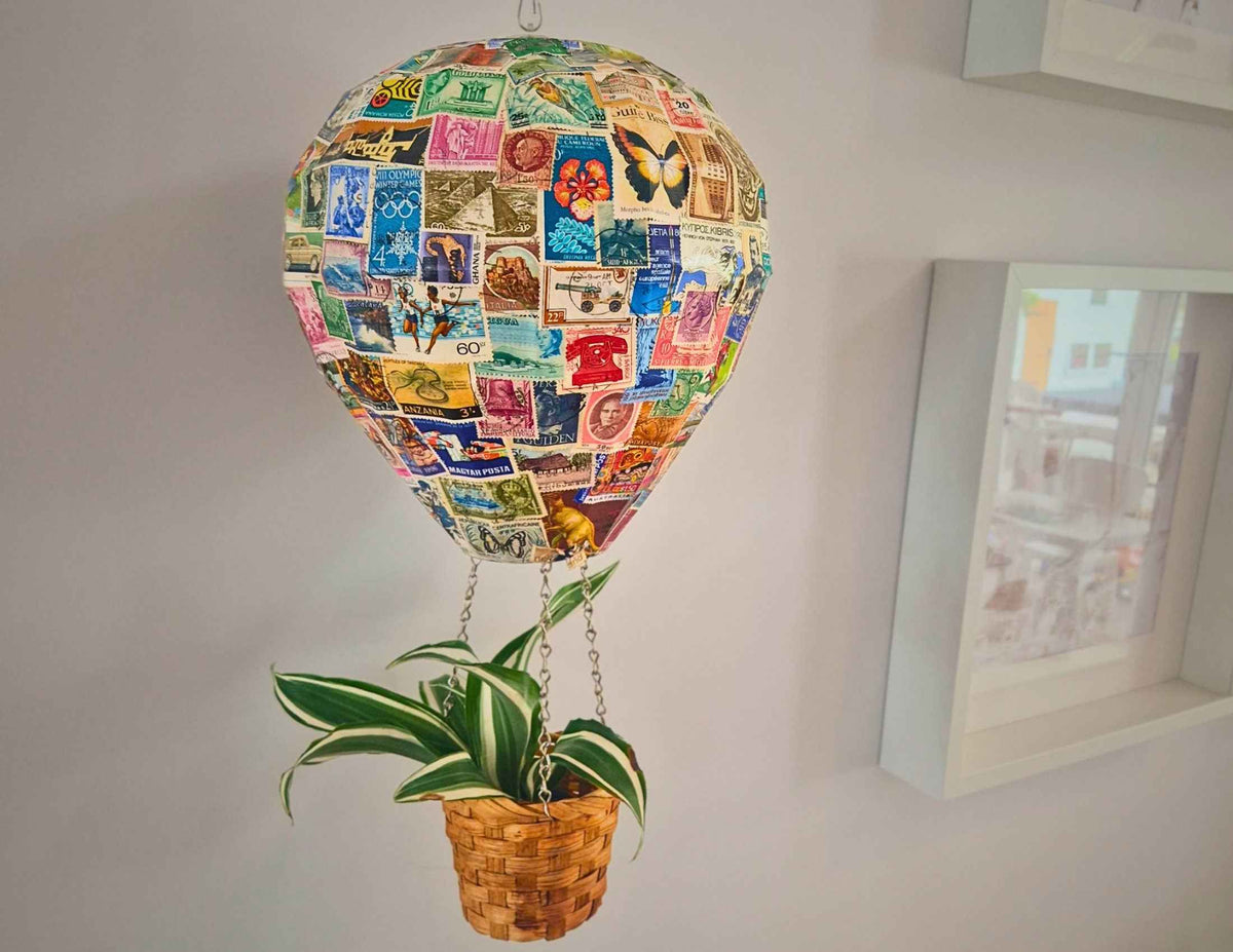 Vintage stamp hot air balloon planter hanging indoors with plant in basket