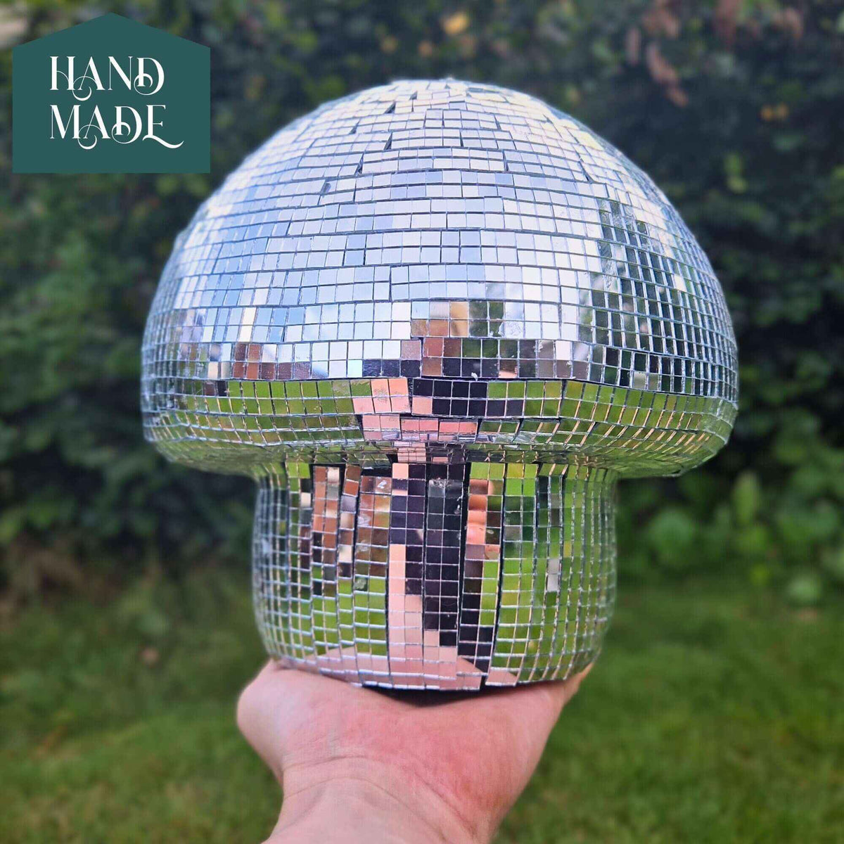 Classic silver disco mushroom ornament held outdoors for scale
