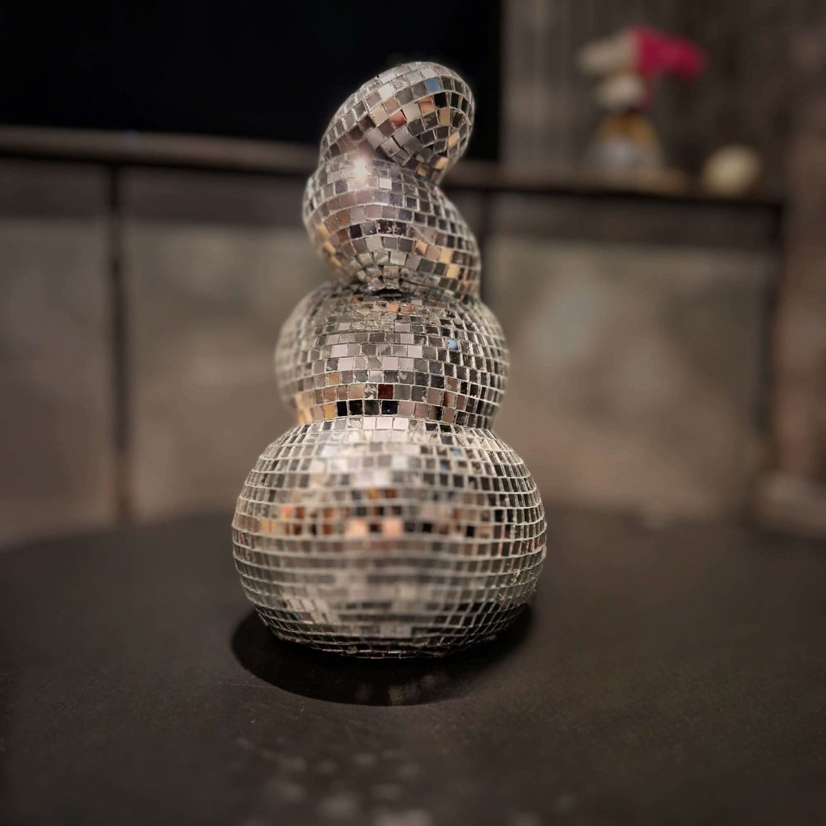 Curved mirror mosaic vase angled on a dark tabletop