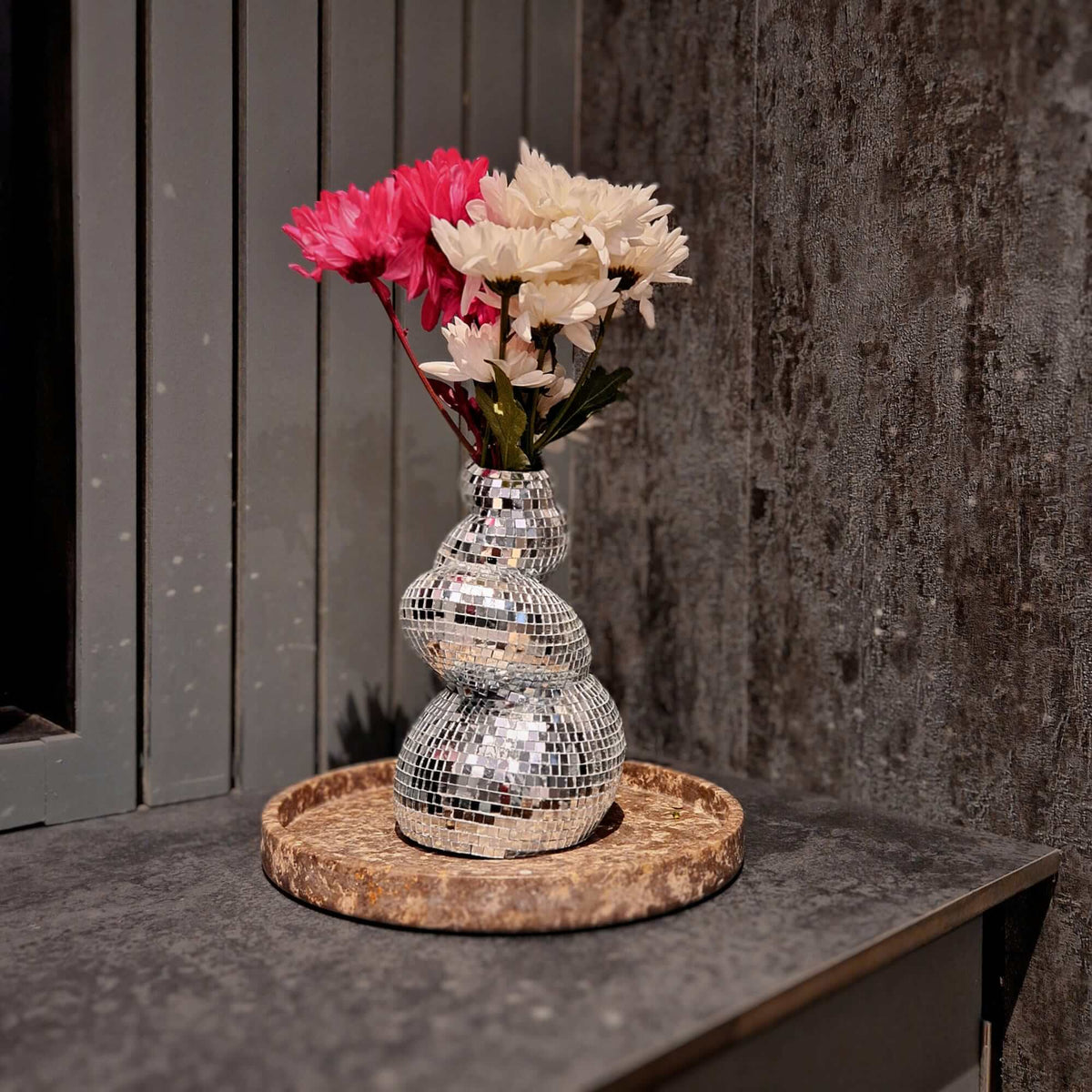 Curved mirror ball flower vase displayed with pink and white flowers