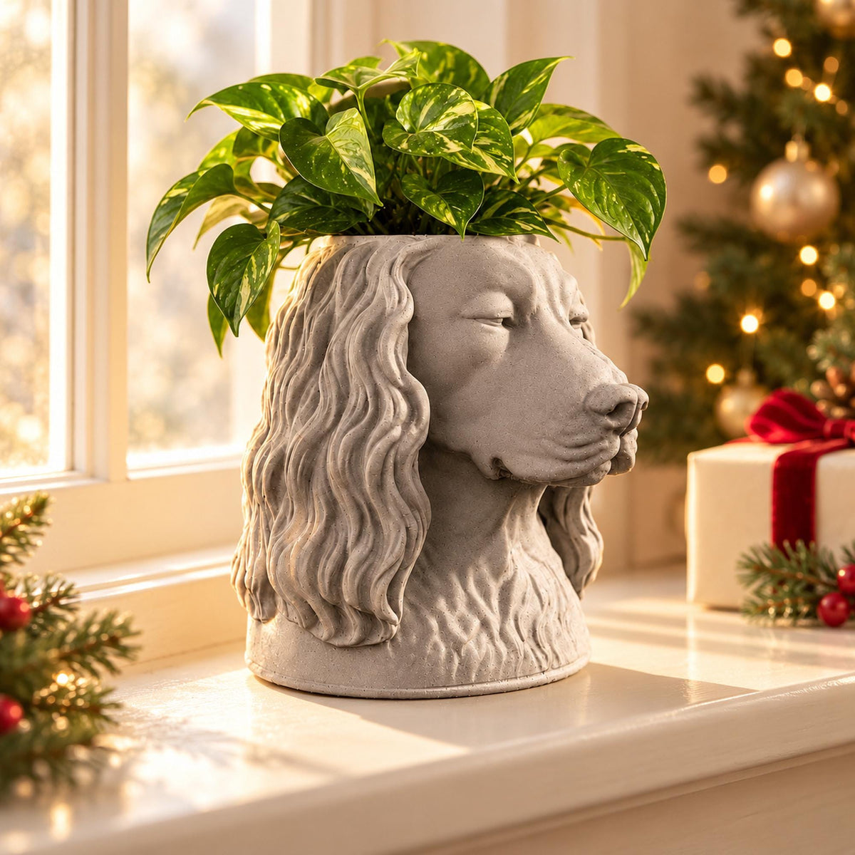 Custom pet stone plant pot shaped like a spaniel, on a windowsill by a Christmas tree