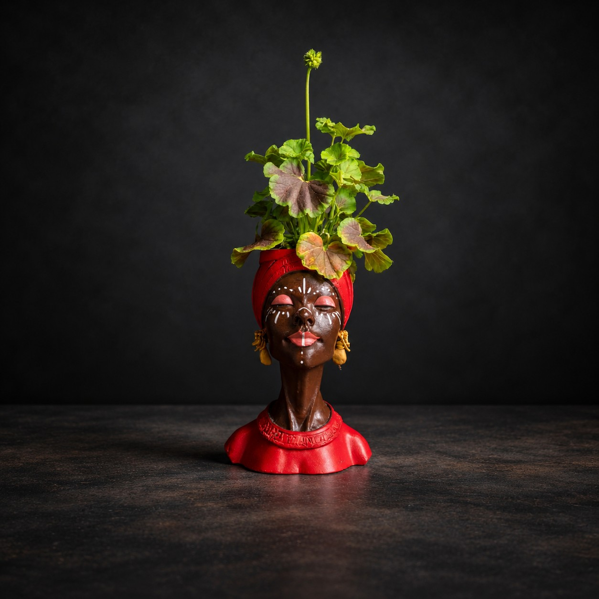 Red Afro woman head planter with gold earrings, planted with pink geraniums
